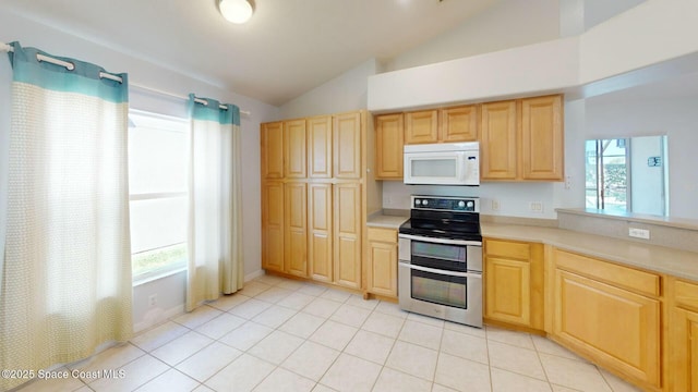 kitchen with light tile patterned flooring, light brown cabinets, lofted ceiling, and electric stove