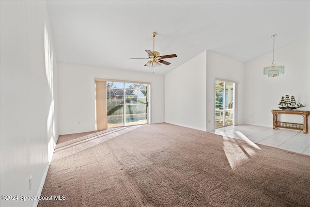 unfurnished living room featuring ceiling fan with notable chandelier, light colored carpet, and vaulted ceiling