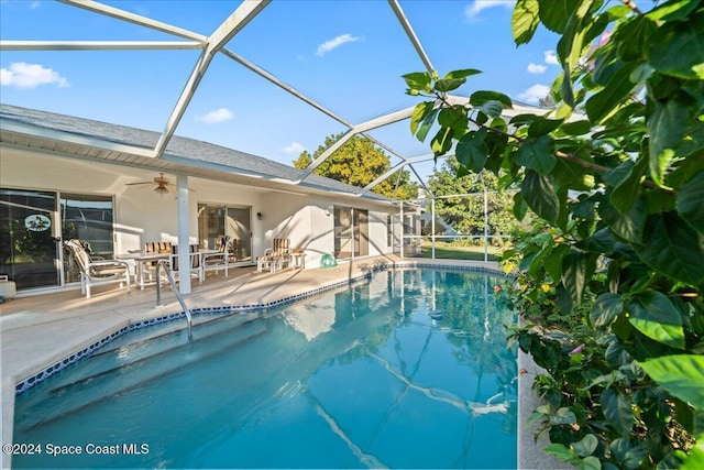 view of pool featuring a patio, glass enclosure, and ceiling fan