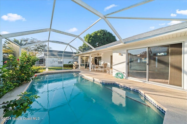 view of swimming pool featuring ceiling fan, a patio area, and glass enclosure