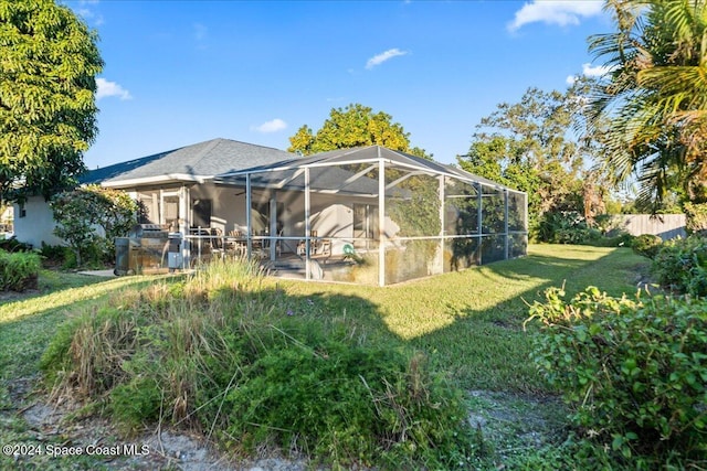 rear view of house with a lawn, a patio area, and a lanai