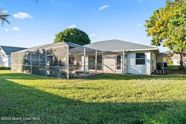 back of house with a yard and a lanai