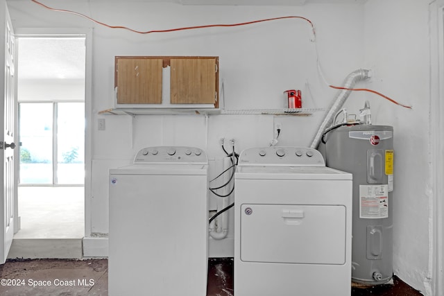 clothes washing area featuring washing machine and dryer, water heater, and cabinets