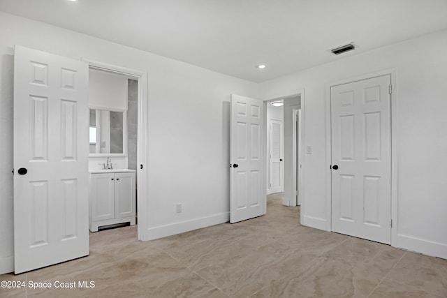 unfurnished bedroom featuring ensuite bath and sink