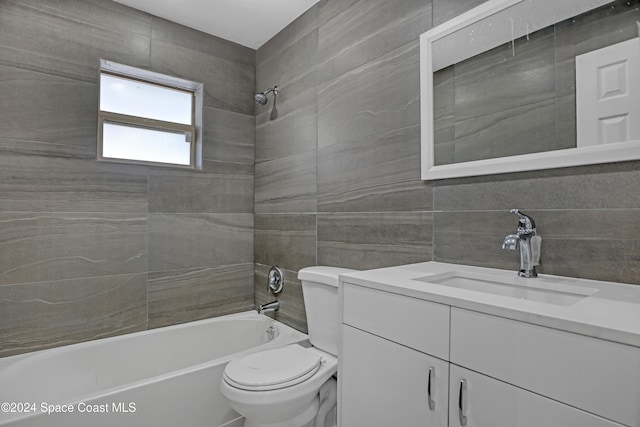 full bathroom with tiled shower / bath combo, toilet, tile walls, and vanity