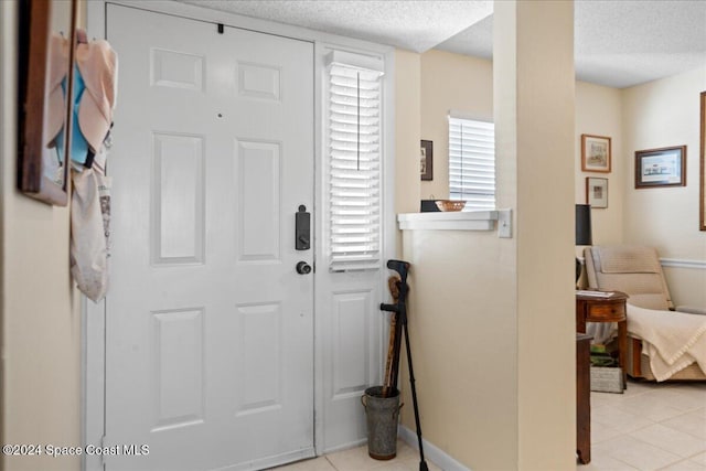 entryway with a textured ceiling and light tile patterned flooring