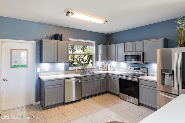 kitchen with gray cabinets, sink, light tile patterned floors, and stainless steel appliances