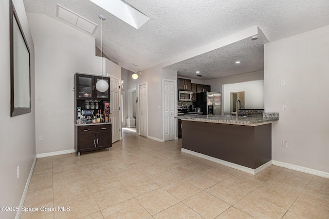 kitchen with kitchen peninsula, sink, stainless steel appliances, and dark brown cabinetry