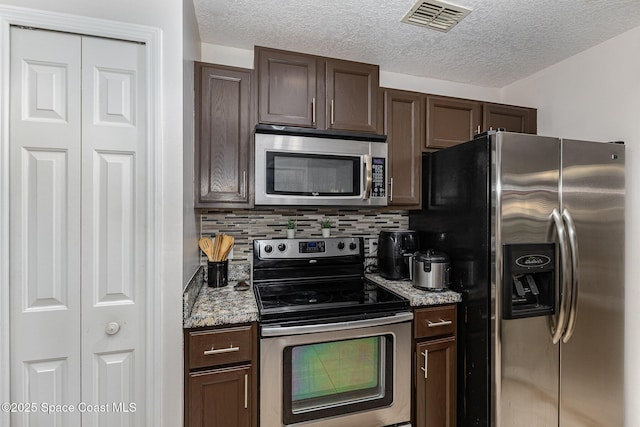 kitchen with light stone counters, appliances with stainless steel finishes, tasteful backsplash, and dark brown cabinetry