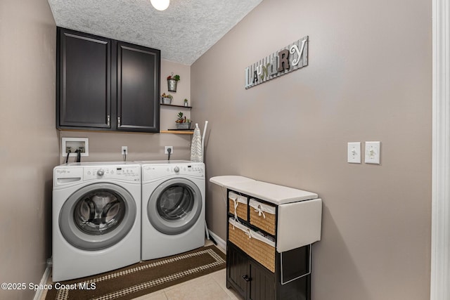 laundry area featuring washing machine and dryer, cabinets, light tile patterned flooring, and a textured ceiling