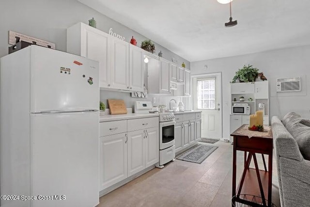 kitchen featuring an AC wall unit, sink, white cabinets, and white appliances