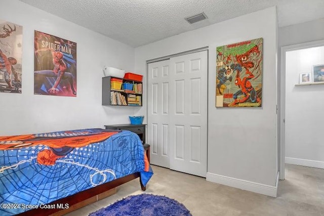 carpeted bedroom featuring a textured ceiling and a closet