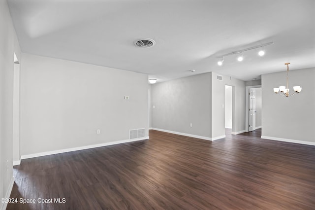 unfurnished room featuring a chandelier, rail lighting, and dark hardwood / wood-style floors