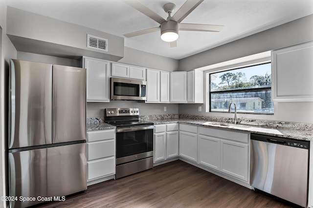 kitchen featuring appliances with stainless steel finishes, light stone counters, dark wood-type flooring, sink, and white cabinetry