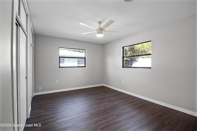 unfurnished bedroom with ceiling fan and dark wood-type flooring