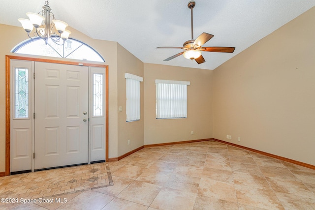 foyer entrance with a textured ceiling, ceiling fan with notable chandelier, vaulted ceiling, and a healthy amount of sunlight