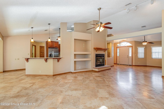 unfurnished living room featuring built in shelves, a textured ceiling, and vaulted ceiling