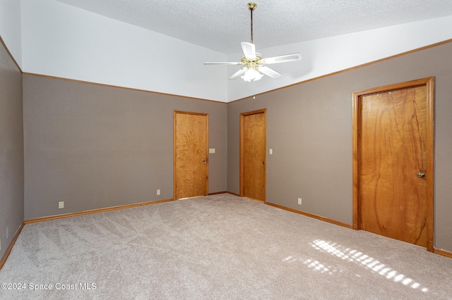 unfurnished bedroom featuring a textured ceiling, ceiling fan, light colored carpet, and vaulted ceiling