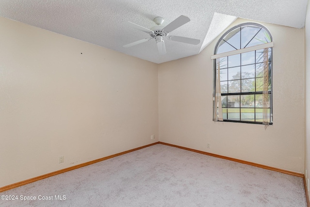 unfurnished room with a textured ceiling, light colored carpet, and vaulted ceiling