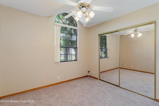 carpeted spare room featuring a textured ceiling, ceiling fan, and vaulted ceiling