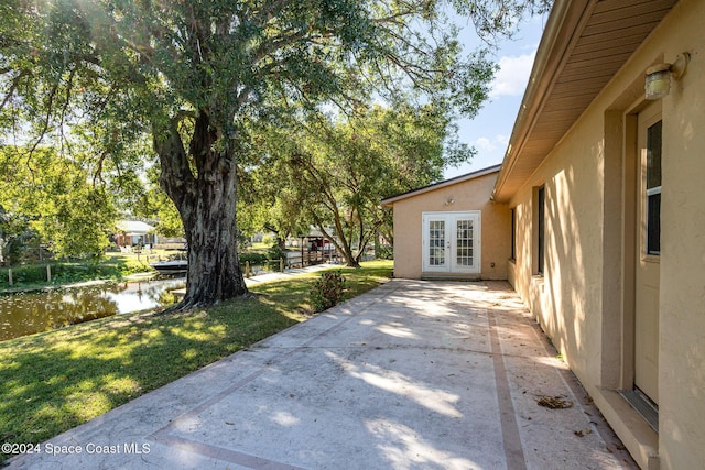 view of yard with a water view and french doors