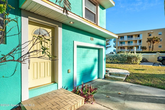 view of exterior entry featuring a garage and stucco siding