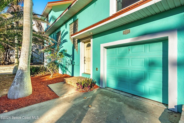 property entrance featuring a garage, driveway, and stucco siding