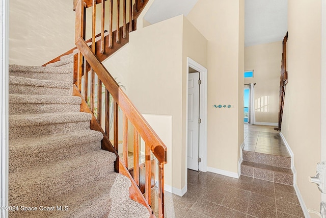 stairs with granite finish floor, a towering ceiling, and baseboards