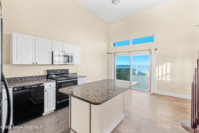 kitchen featuring dark stone countertops, white cabinets, a kitchen island, and black appliances