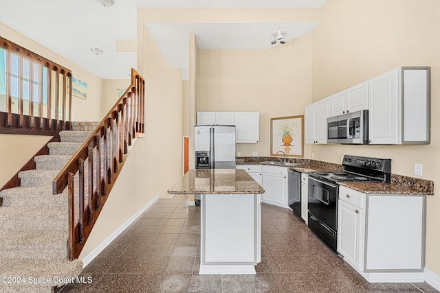 kitchen featuring white cabinets, a sink, a kitchen island, black appliances, and baseboards