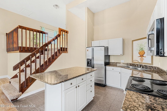 kitchen featuring appliances with stainless steel finishes, white cabinets, a sink, and granite finish floor