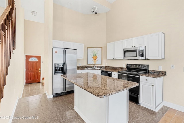 kitchen with a kitchen island, white cabinets, a sink, and black appliances