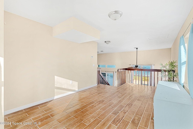 hall with wood tiled floor, baseboards, plenty of natural light, and an upstairs landing