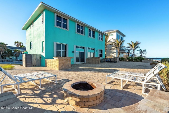 rear view of house featuring a patio, a fire pit, and stucco siding