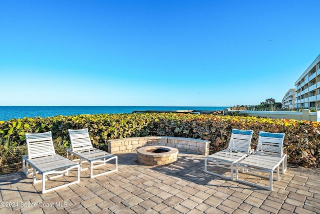 view of patio with a water view and a fire pit