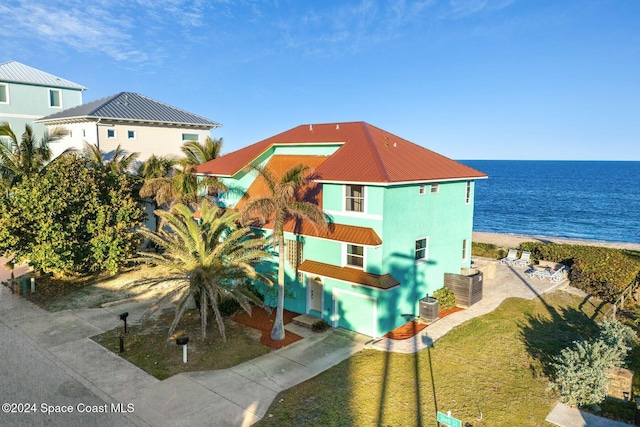 exterior space featuring central AC, a water view, and a beach view