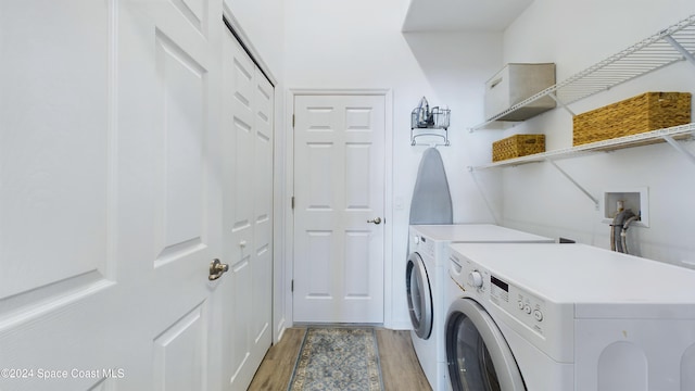 laundry area featuring washing machine and clothes dryer and light hardwood / wood-style floors