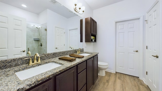 bathroom featuring hardwood / wood-style floors, an inviting chandelier, a shower with shower door, vanity, and toilet