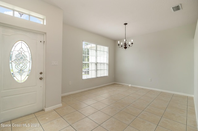 tiled foyer featuring a notable chandelier