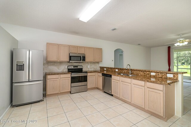 kitchen featuring light stone countertops, sink, ceiling fan, stainless steel appliances, and kitchen peninsula