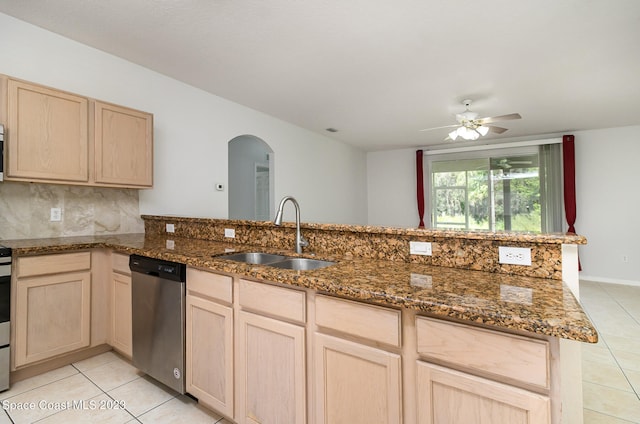 kitchen featuring ceiling fan, sink, stainless steel dishwasher, kitchen peninsula, and dark stone countertops