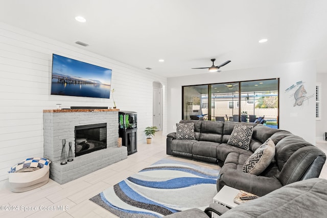 living room with a brick fireplace and ceiling fan