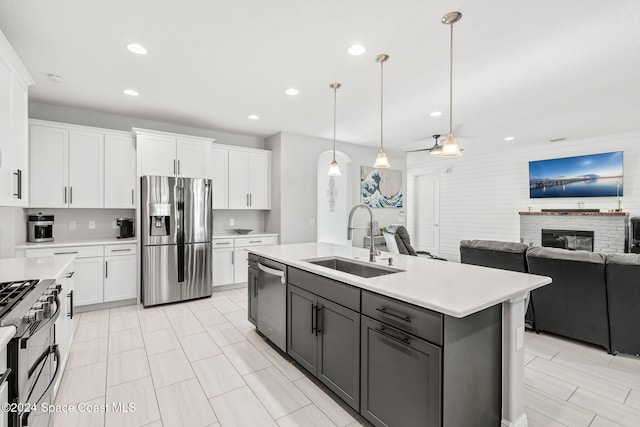 kitchen featuring ceiling fan, sink, decorative light fixtures, white cabinets, and appliances with stainless steel finishes