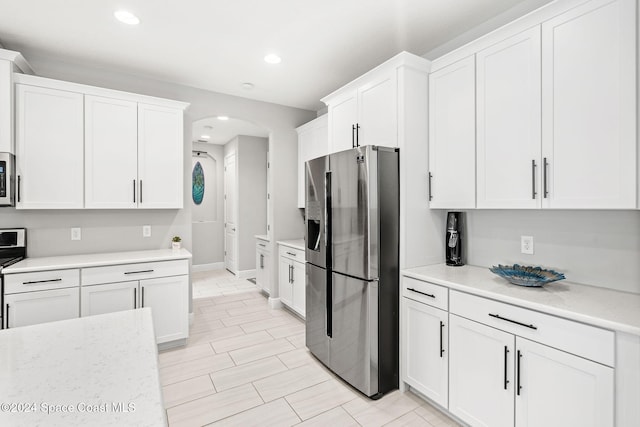 kitchen with light stone countertops, white cabinets, and stainless steel appliances