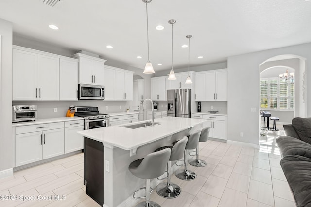 kitchen with pendant lighting, a breakfast bar, a kitchen island with sink, sink, and stainless steel appliances