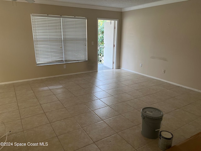 empty room featuring light tile patterned floors and crown molding