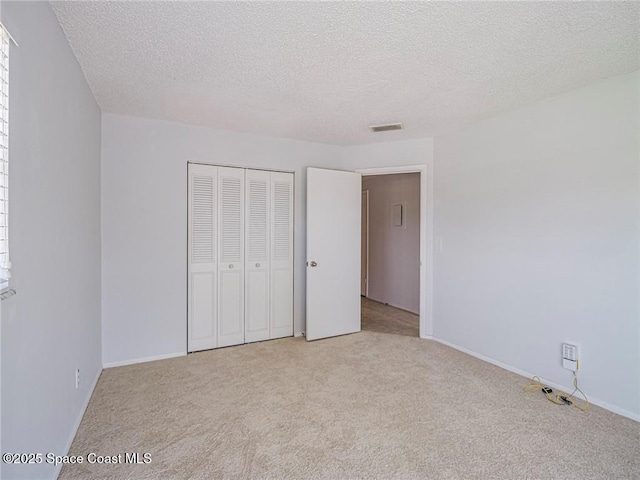 28 Pine Arbor Ln Unit 206, Vero Beach, FL 32962 - unfurnished bedroom with baseboards, a closet, a textured ceiling, and light colored carpet
