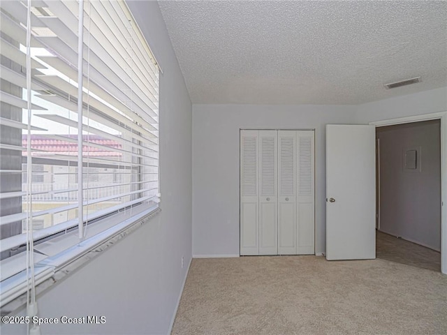 28 Pine Arbor Ln Unit 206, Vero Beach, FL 32962 - unfurnished bedroom with visible vents, carpet flooring, a textured ceiling, and a closet