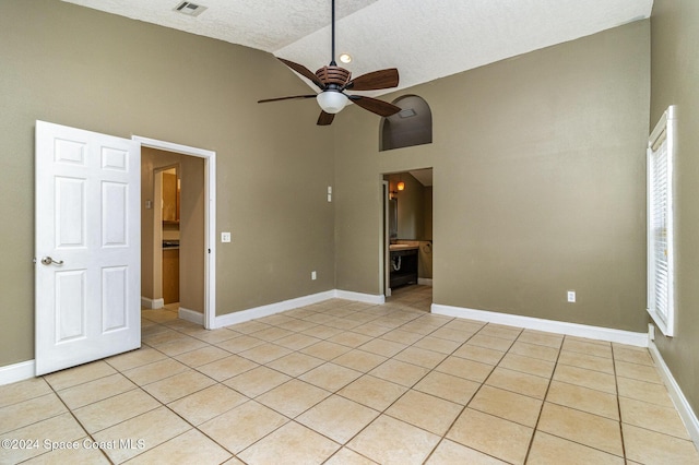 empty room with high vaulted ceiling, ceiling fan, light tile patterned floors, a textured ceiling, and a wealth of natural light