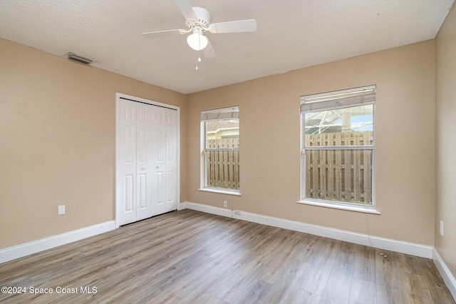 unfurnished bedroom featuring ceiling fan, light wood-type flooring, a textured ceiling, and a closet